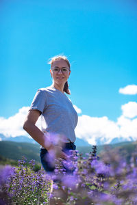 Portrait of woman with pink flowers against blue sky