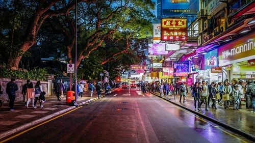 People walking on footpath in city at night