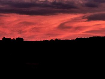 Silhouette landscape against dramatic sky during sunset