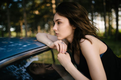 Hipster woman is resting on vintage car closeup