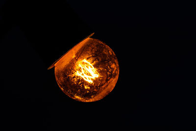 Low angle view of illuminated light bulb against black background