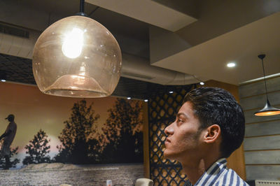 Portrait of young man looking away at illuminated lamp