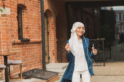 Full length of smiling young woman in city