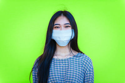 Portrait of beautiful young woman against green background