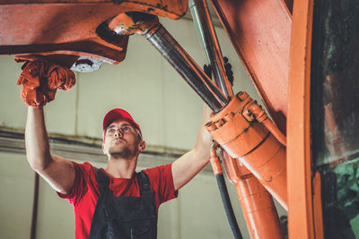 Young man repairing machinery in factory