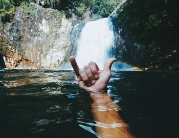 Person hand against waterfall