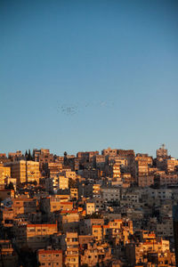 Buildings in city against clear blue sky