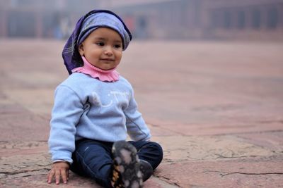 Portrait of cute girl sitting on footpath