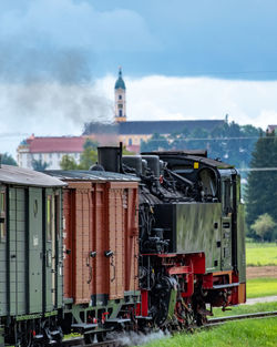 Narrowgauge steamtrain in front of baroque monastery