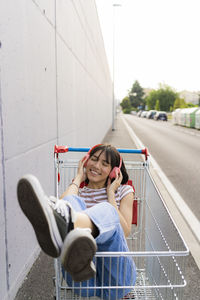 Smiling woman with eyes closed listening music in shopping cart