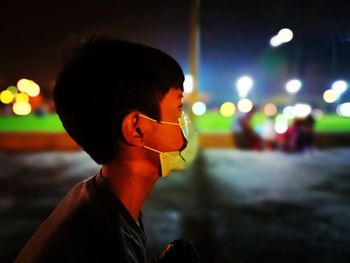 Portrait of young man looking away on street at night