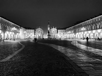 People in illuminated city against sky