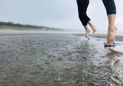 Low section of people jumping at beach