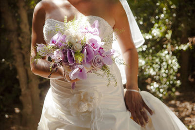 Midsection of bride holding flower bouquet