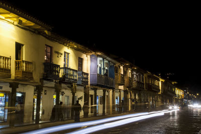 Light trails on street amidst buildings in city at night