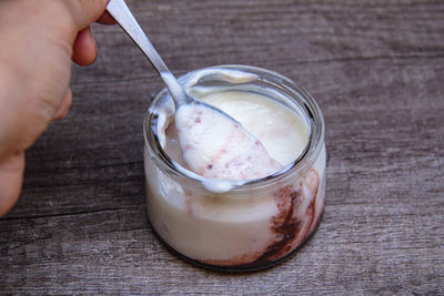 Midsection of person holding ice cream on table