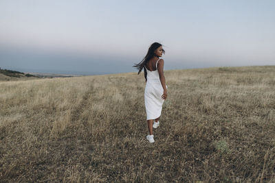 Full length of woman standing on field against sky