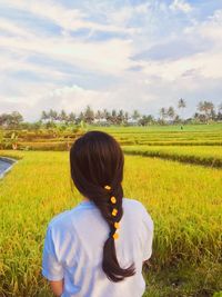 Rear view of woman standing on field against sky