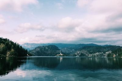 Scenic view of lake and mountains against cloudy sky