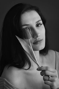 Portrait of beautiful woman holding face against black background