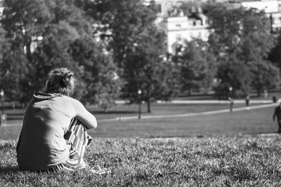 Rear view of woman sitting on grass