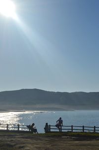 Silhouette people on beach against clear sky