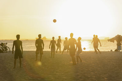Young people playing beach soccer during sunset at ribeira beach in salvador, bahia, brazil.