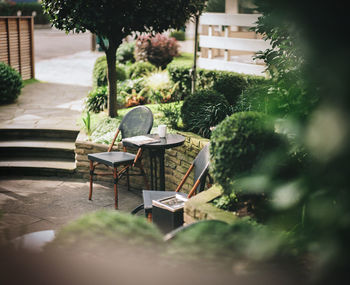 Close-up of chairs and table against trees