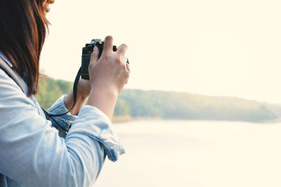 Midsection side view of woman photographing lake