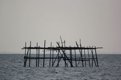 Wooden structure in sea against clear sky