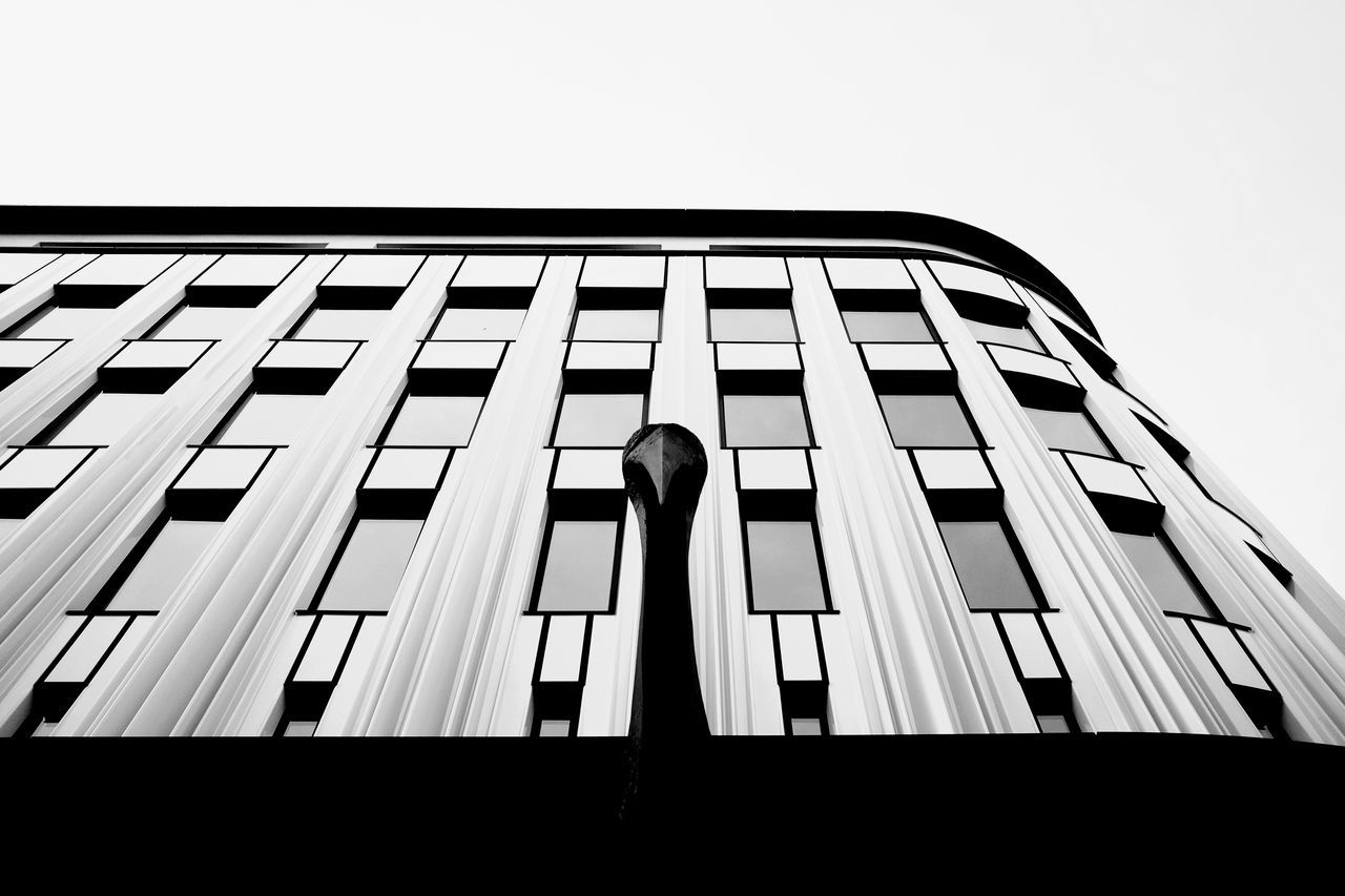 LOW ANGLE VIEW OF WOMAN STANDING BY BUILDING AGAINST SKY