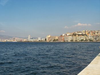 Sea by cityscape against sky