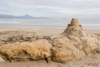 Rock formations on shore against sky