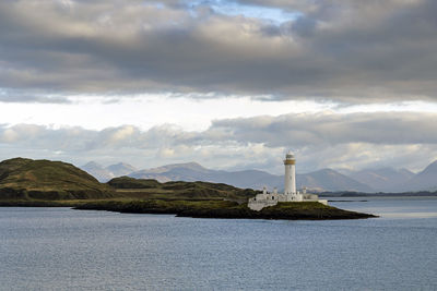 Lighthouse by sea against sky