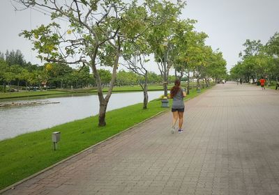 Rear view of woman walking on riverbank