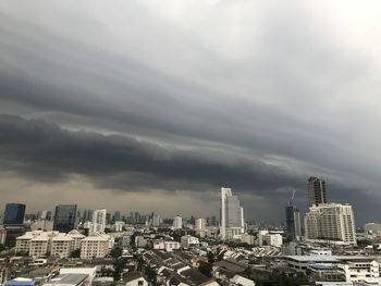 Aerial view of buildings in city against cloudy sky