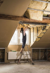 Young woman mounting insulation in her new home