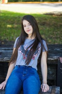 Portrait of young woman sitting on bench at park