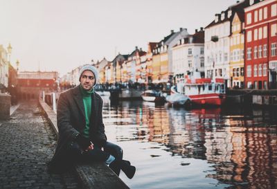 Man looking away while sitting by canal