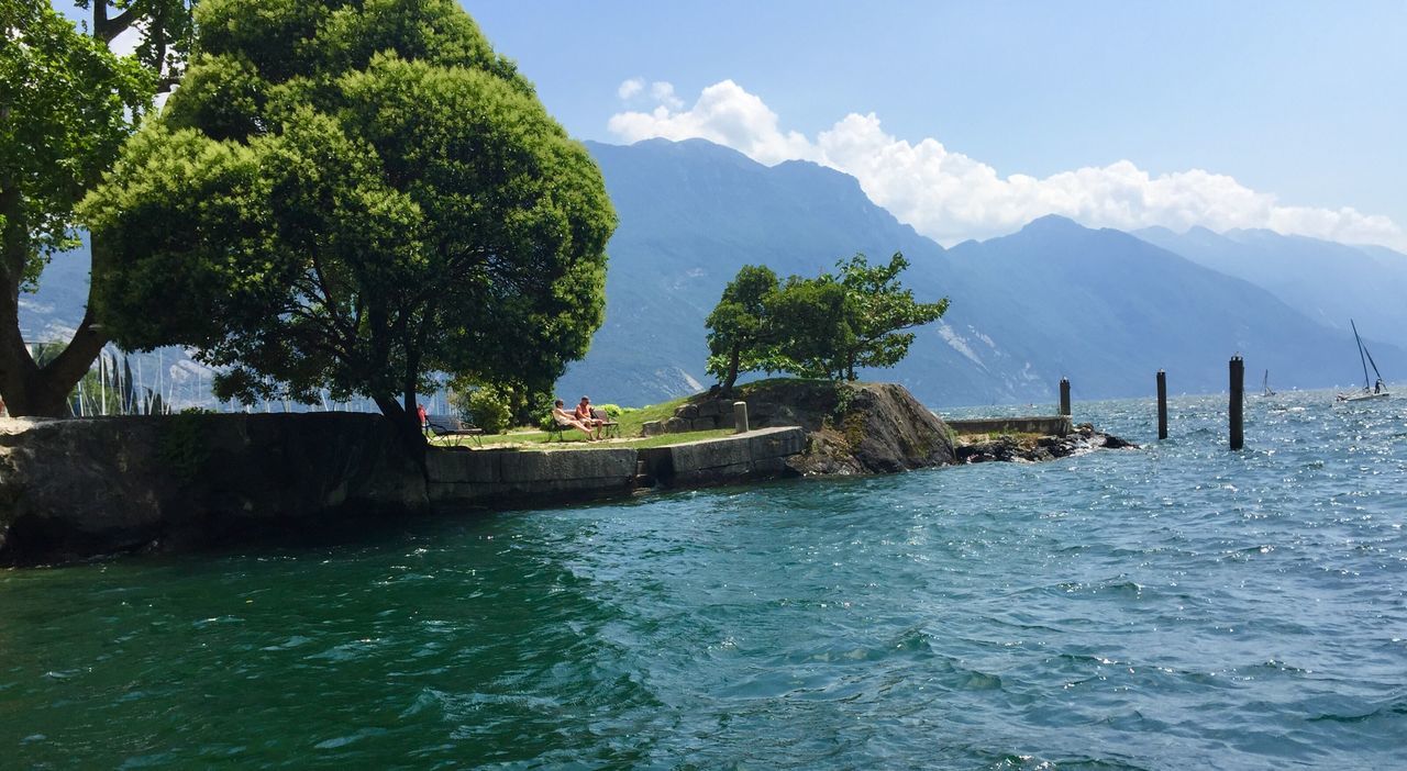 water, sky, mountain, tree, tranquility, tranquil scene, scenics, nature, beauty in nature, cloud, cloud - sky, day, rippled, idyllic, outdoors, non-urban scene, remote, mountain range, green color, blue, tourism, non urban scene, travel destinations, growth