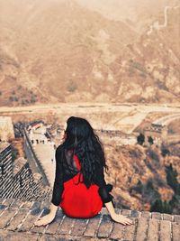 Rear view of woman sitting against wall