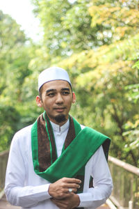 Man in traditional clothing standing against trees