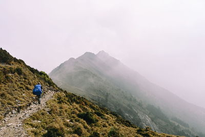 Rear view of man riding on mountain against sky