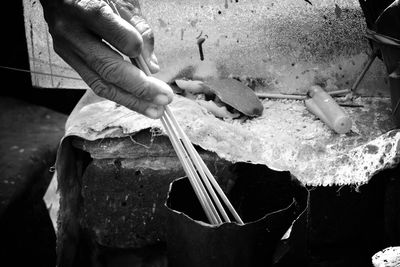 Cropped hand of person burning incense sticks at temple