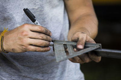 Construction worker using speed square to measure angle on steel.