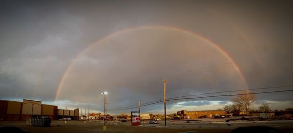Rainbow over illuminated street light against cloudy sky
