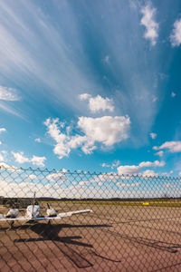 Airplane at runway against cloudy sky