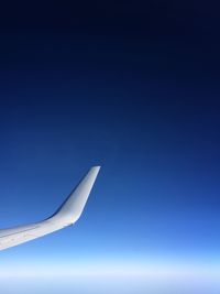 Airplane wing against clear blue sky