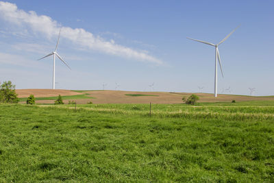 Windmills on field against sky