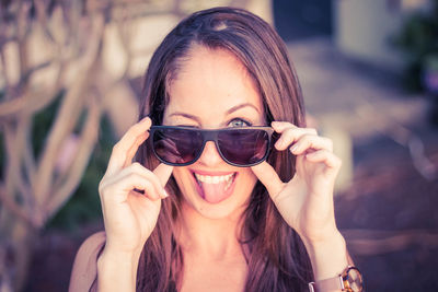Portrait of woman wearing sunglasses while sticking out tongue